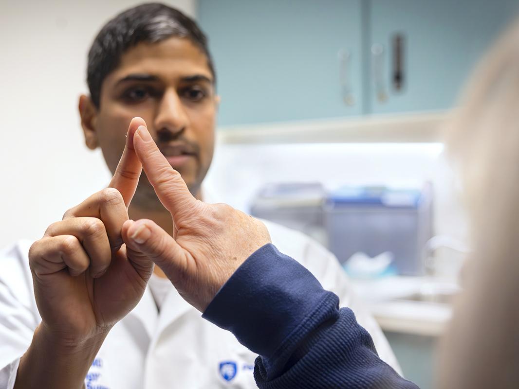 A doctor wearing a white coat touches his index finger to a patient’s index finger to test her coordination. 