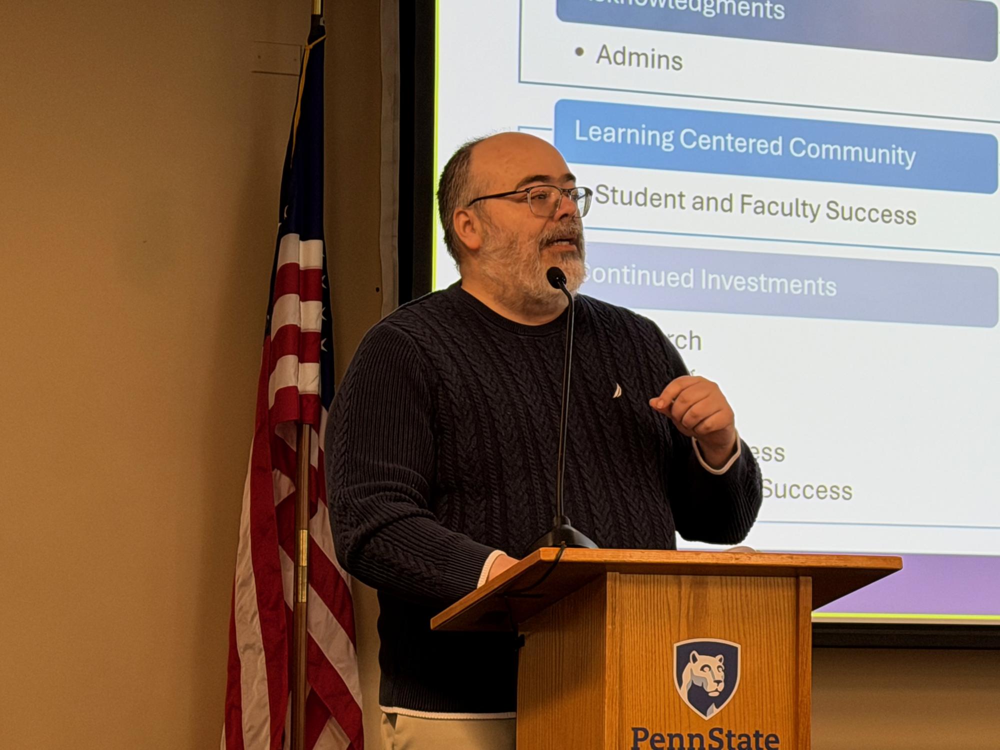 Anibal Torres speaking at a podium in front of a screen