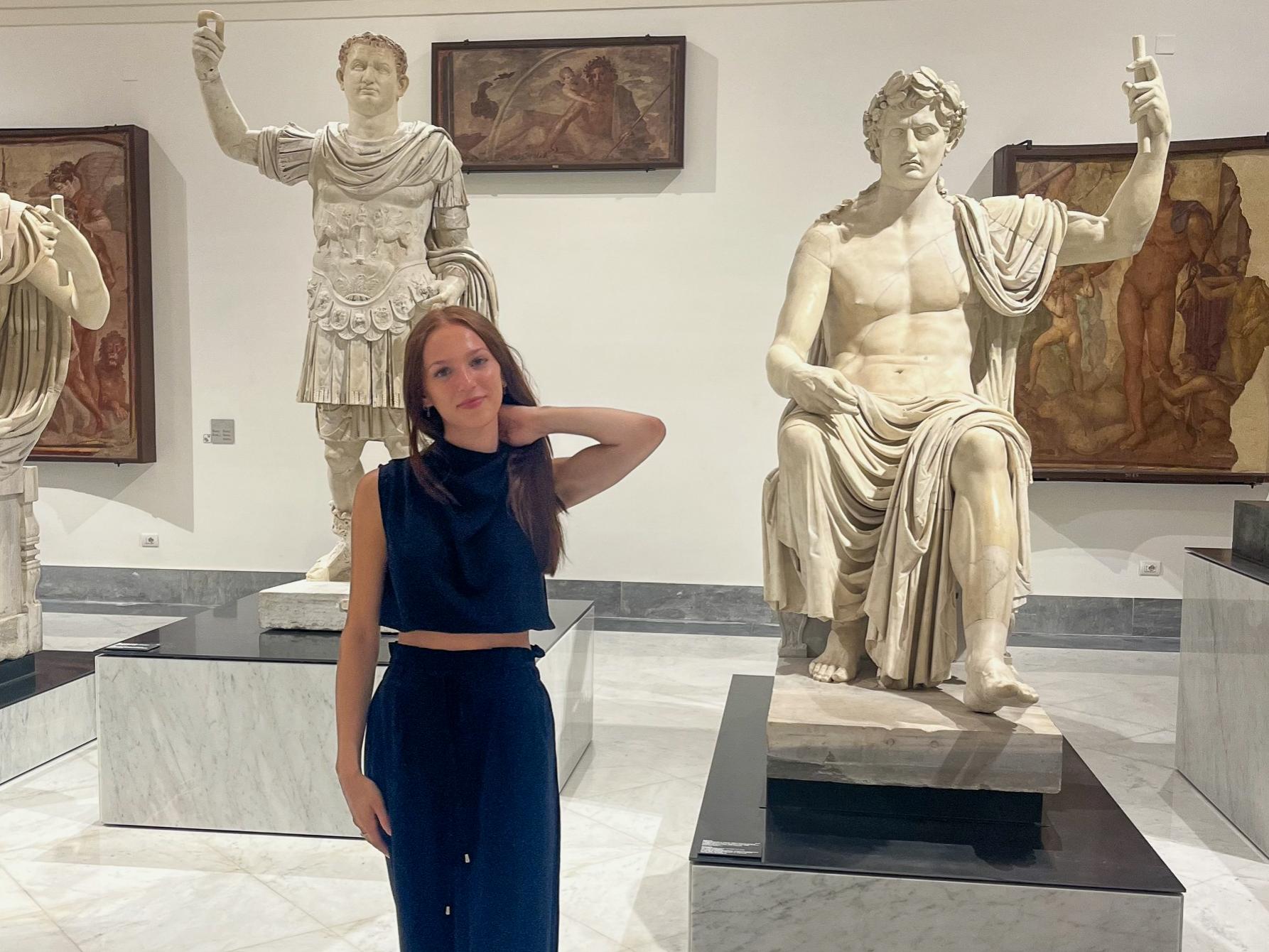 Alexis Wilson poses in front of statues at a museum in Salerno, Italy.