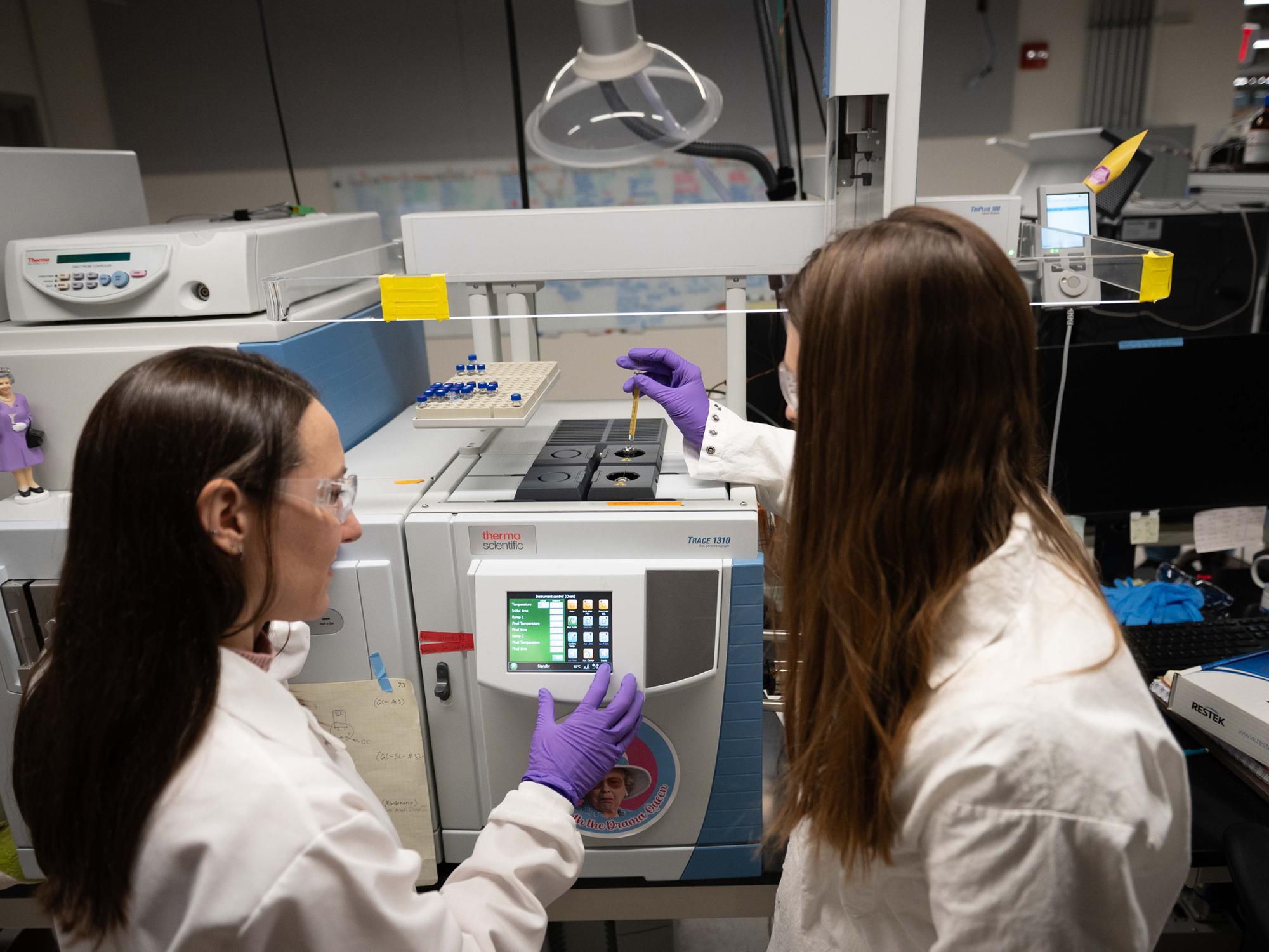 Two scientists working at an instrument 