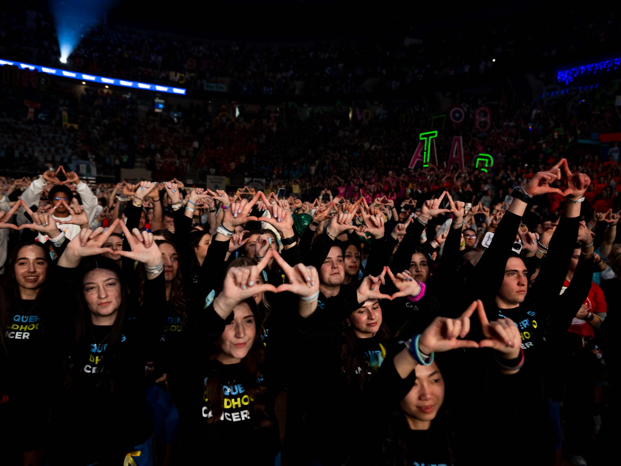 A crowd of people hold up their hands to form a diamond