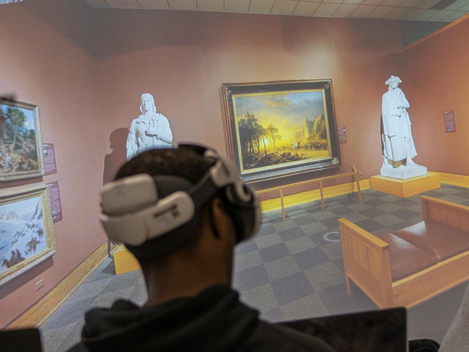 a student wearing a VR headset in front of a screen showing a museum exhibit