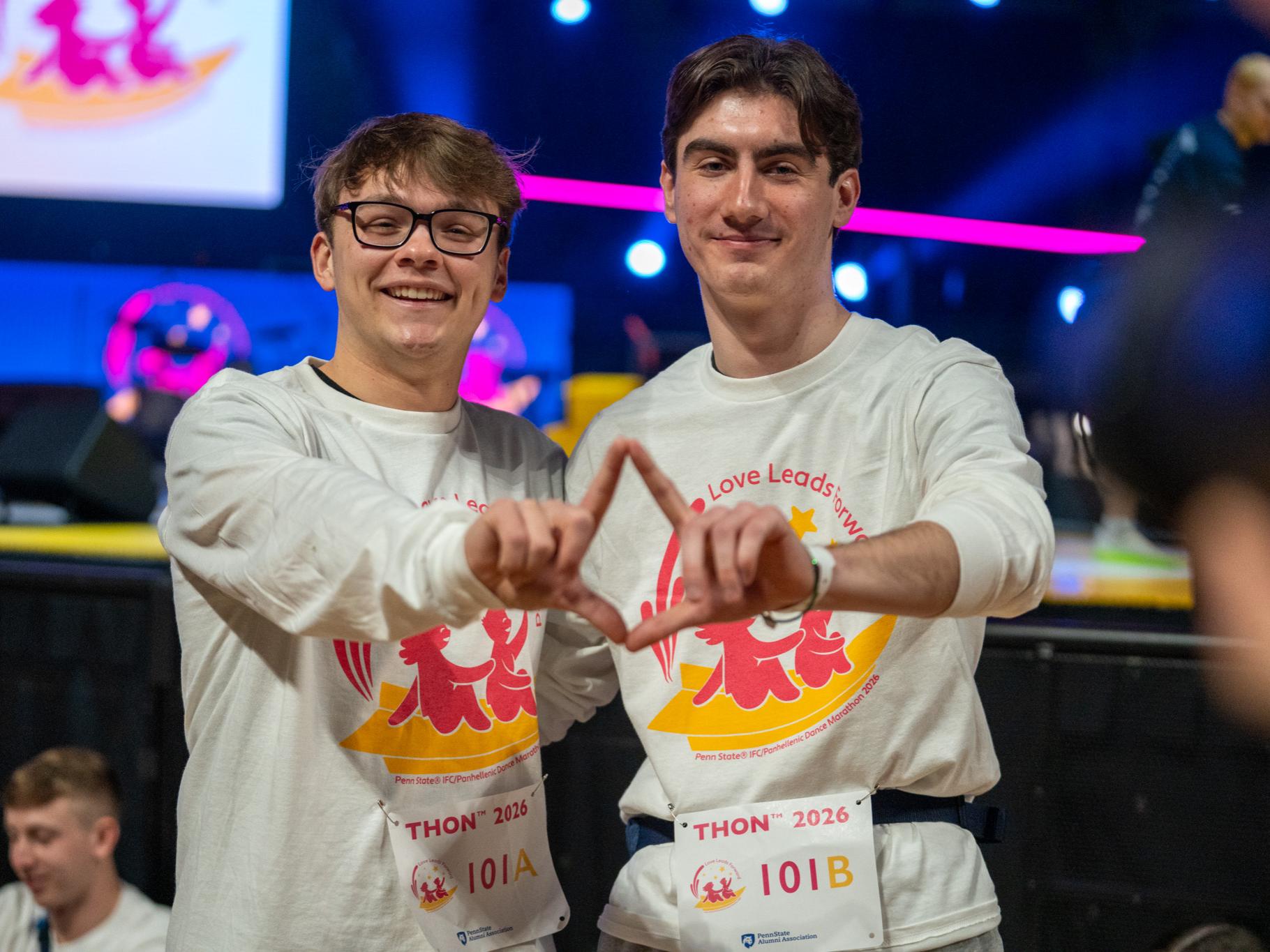 Two people standing together and forming a diamond with their fingers