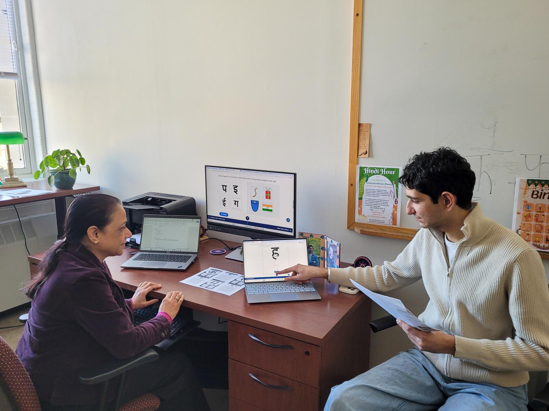 Bhavya Aplash sits while pointing to a laptop screen that Lecturer of Hindi and Asian Studies Ritu Jayakar is also looking at while the two work on the Hindi Script Learning Tool.