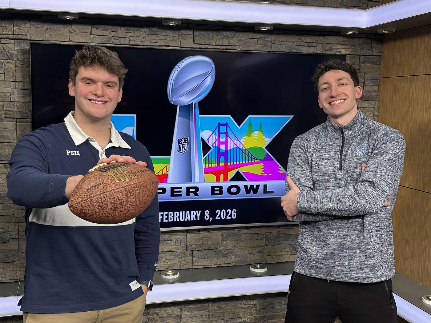 Two students standing in front of a TV monitor 