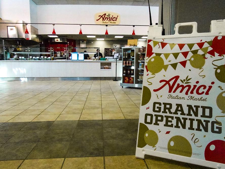 Entrance to Amici Italian Market with sandwich board sign that reads "Amici Italian Market Grand Opening"