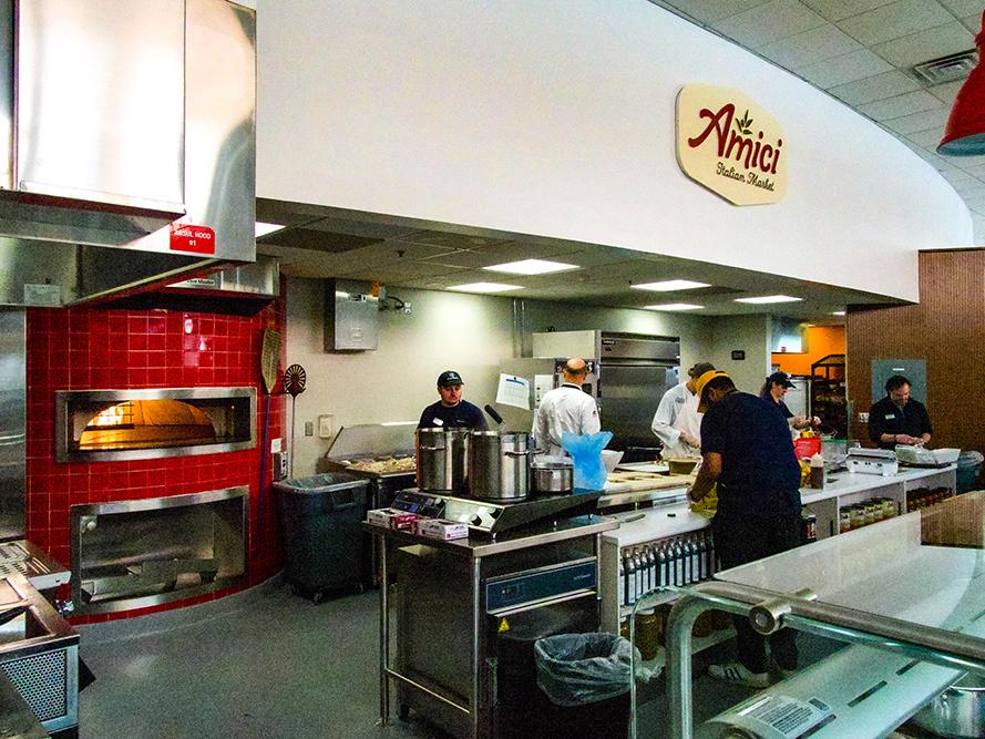 Employees working at Amici Italian Market with oven in the background