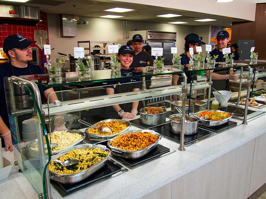 Employees at Amici Italian Market with female employee smiling.