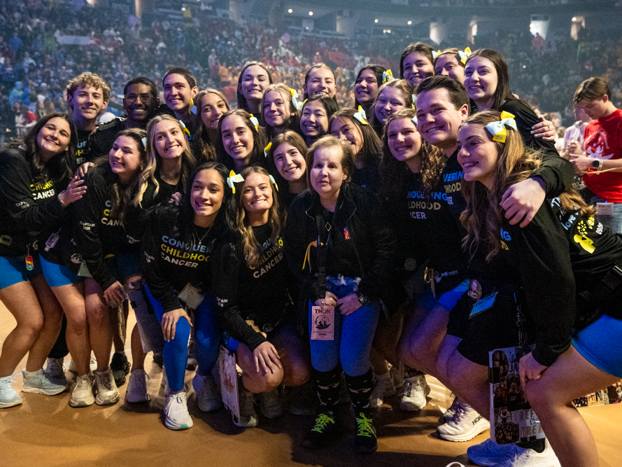 A group of people stand together smiling towards the camera