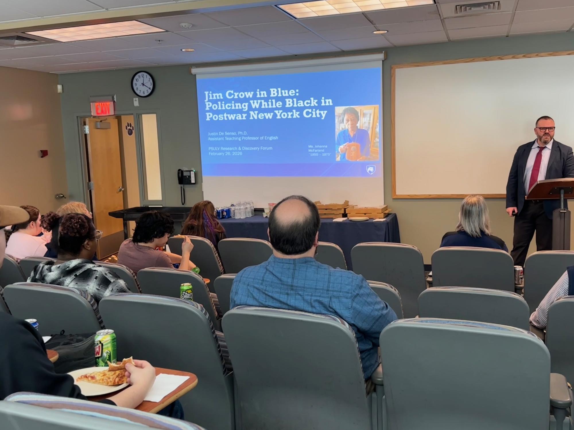 man speaking in front of a small lecture hall