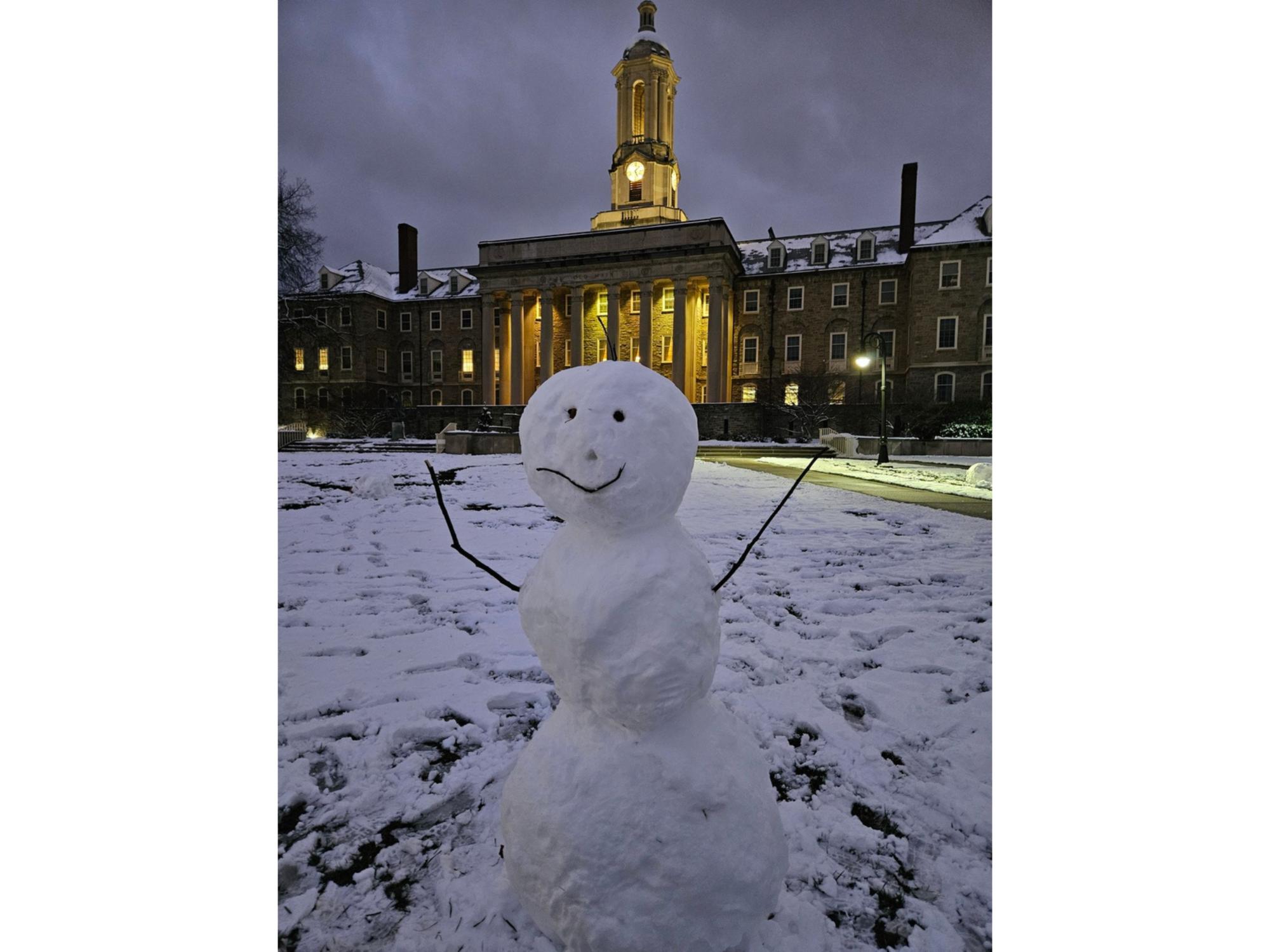 A closeup shot of a snowman in front of Old Main on Penn State's University Park campus