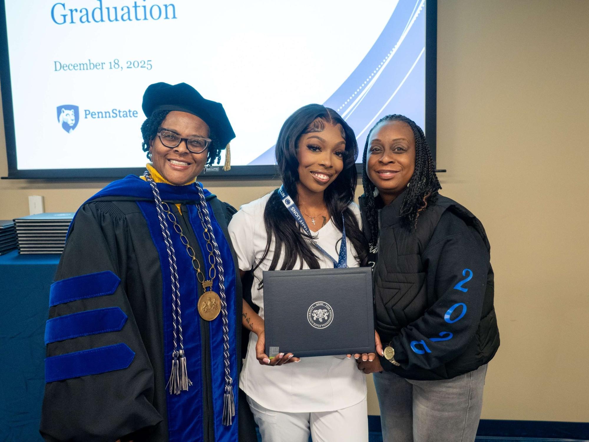 three people standing together with one holding a certificate