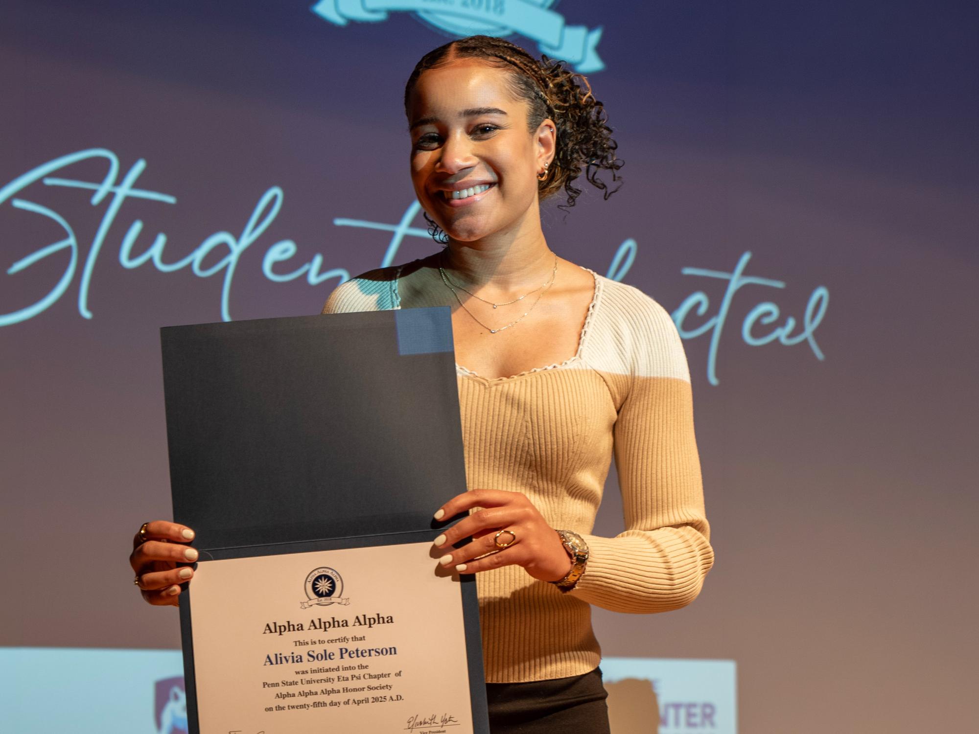 Alivia Peterson holds a certificate showing she’s been inducted at the spring 2025 Tri-Alpha Induction Ceremony.