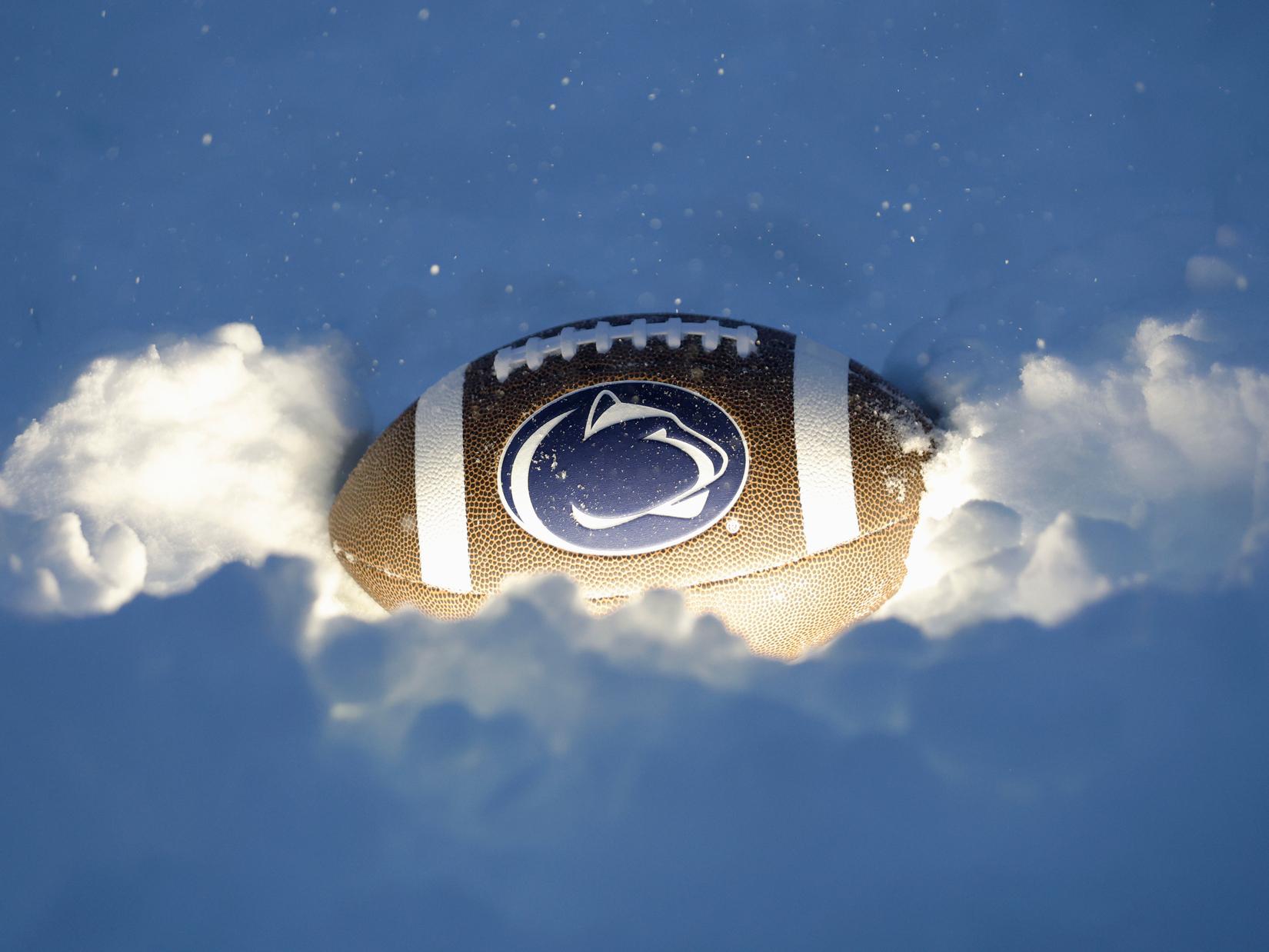 A picture of a football with a Penn State logo on it sits in the snow