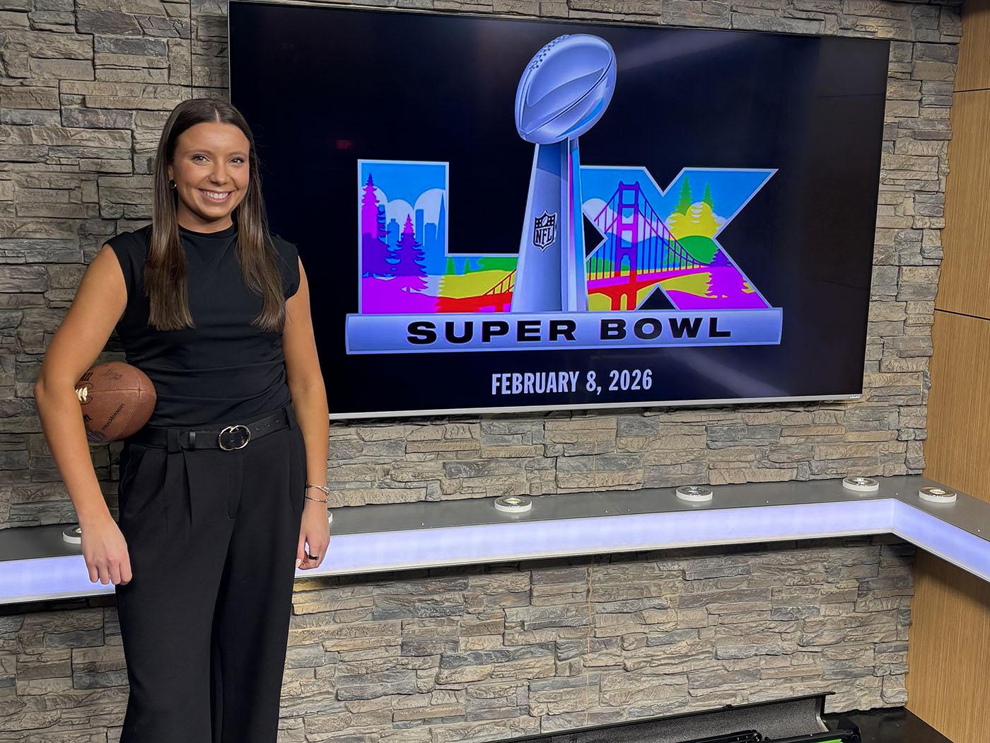 Girl wearing all black with football under her right arm.