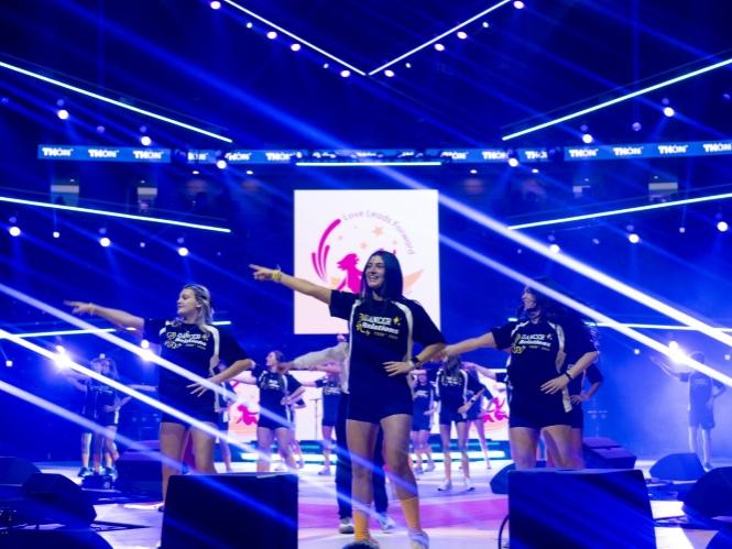 Three students lead a dance on a stage