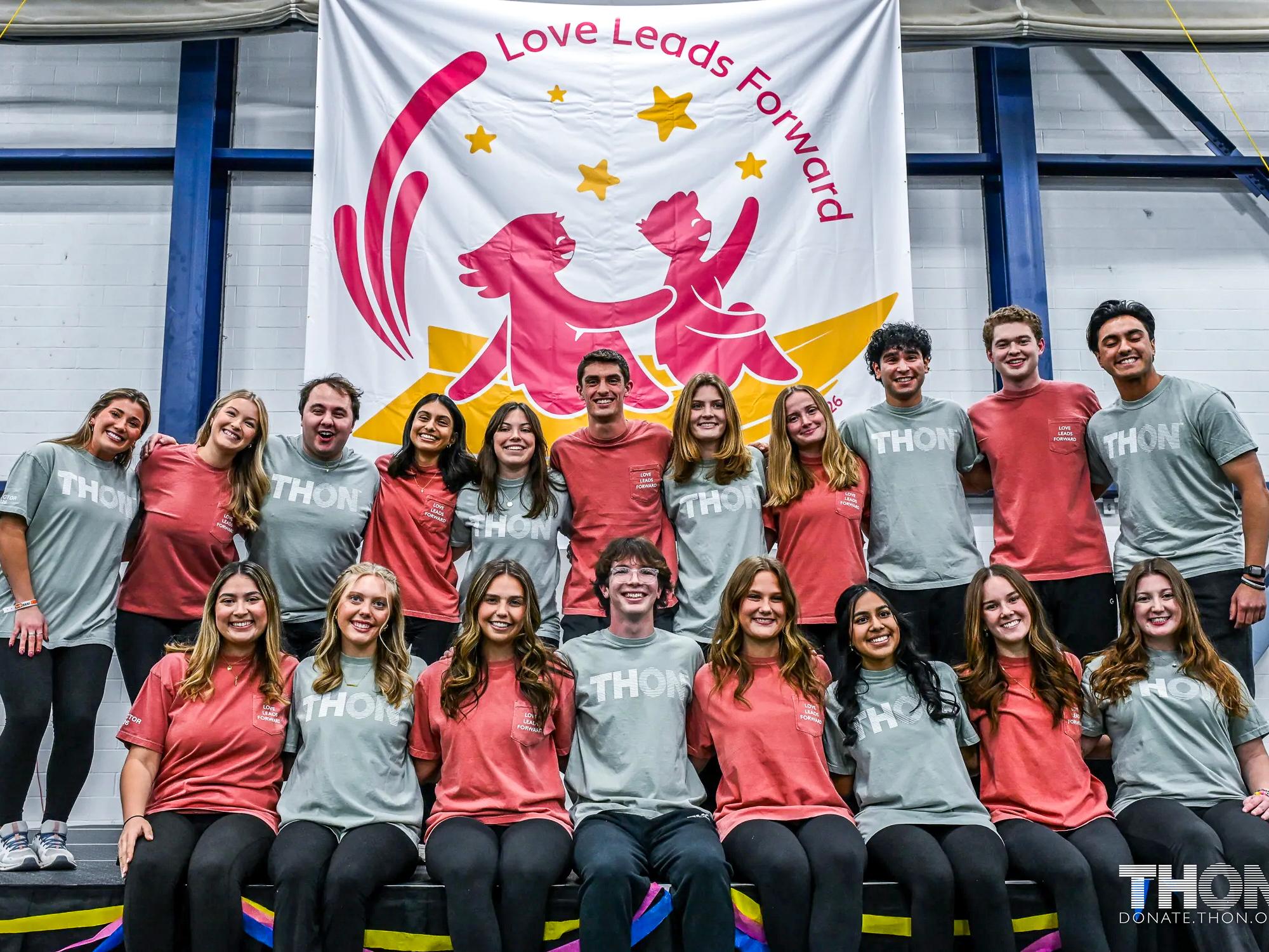 THON Directors stand in front of the Love Leads Forward sign.