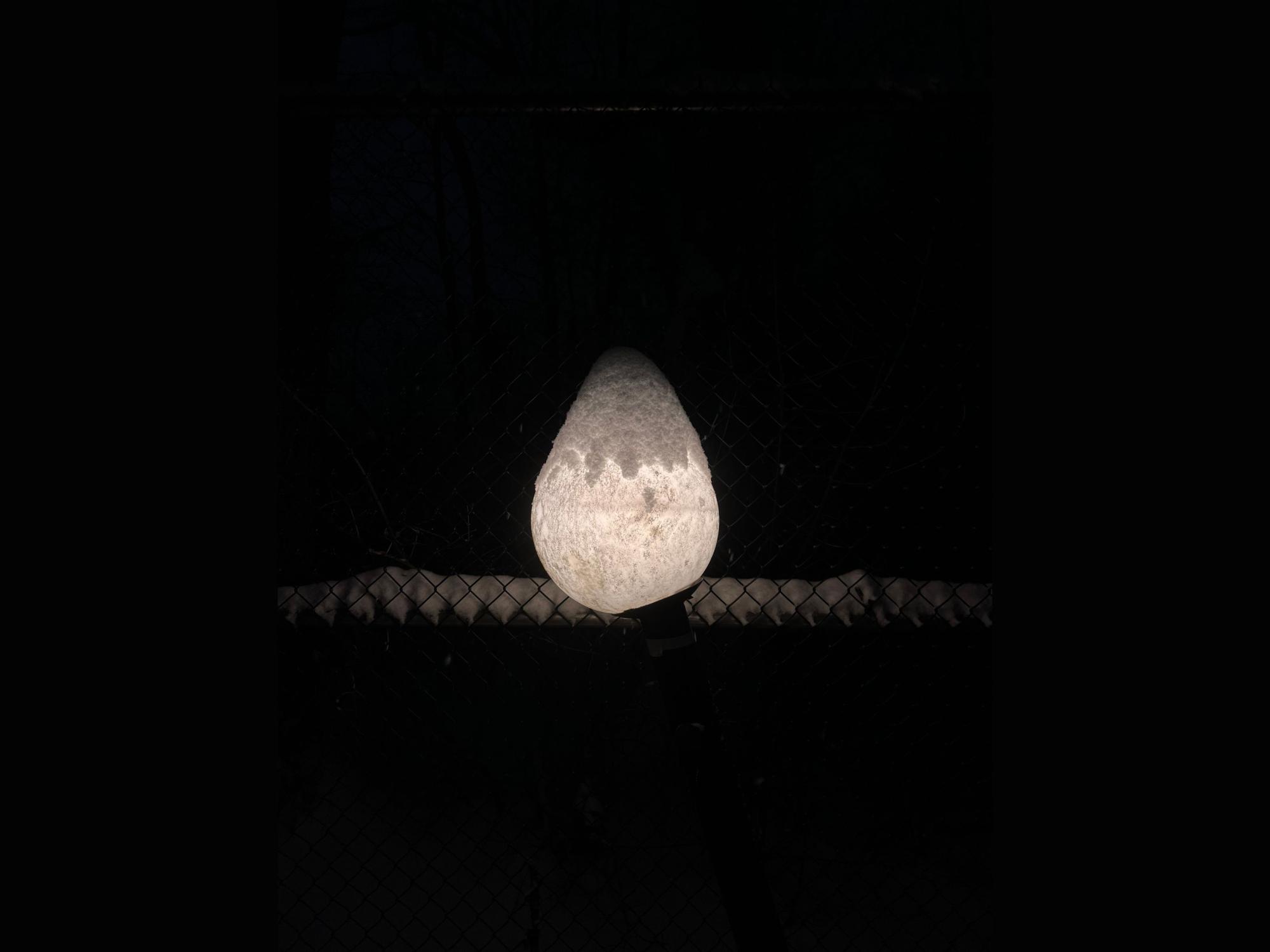 A snow covered light shines
