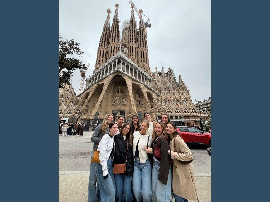 Jessica Amatrudo wears jeans, a black top and a brown purse while standing with a group of friends in front of the Basílica de la Sagrada Família in Barcelona.