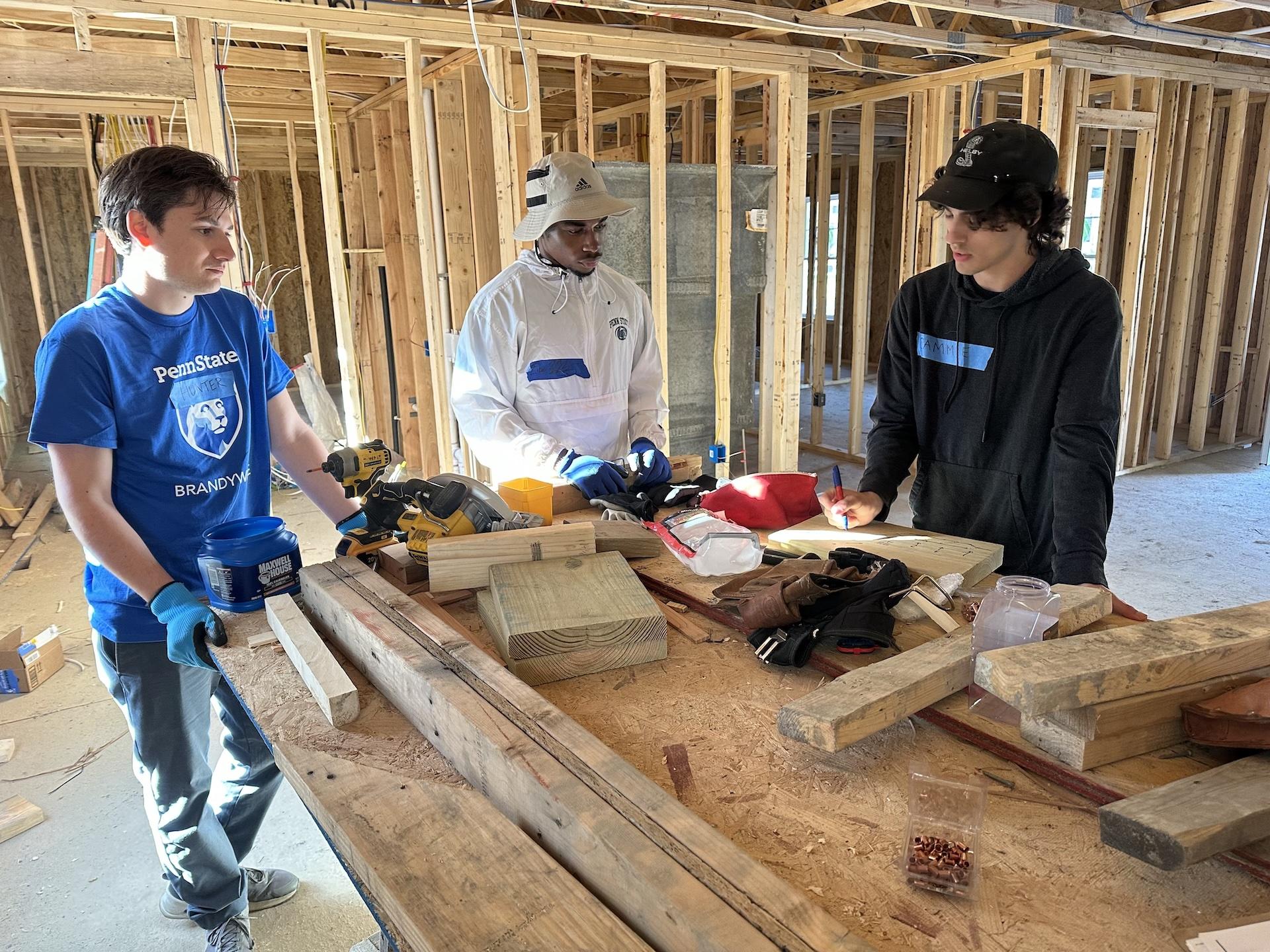 three students standing around a wooden table
