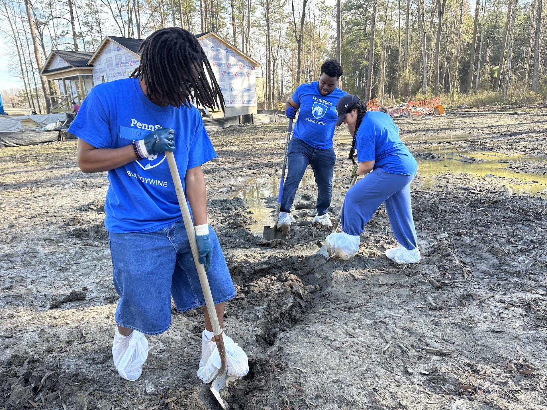 three students digging a hole in the dirt