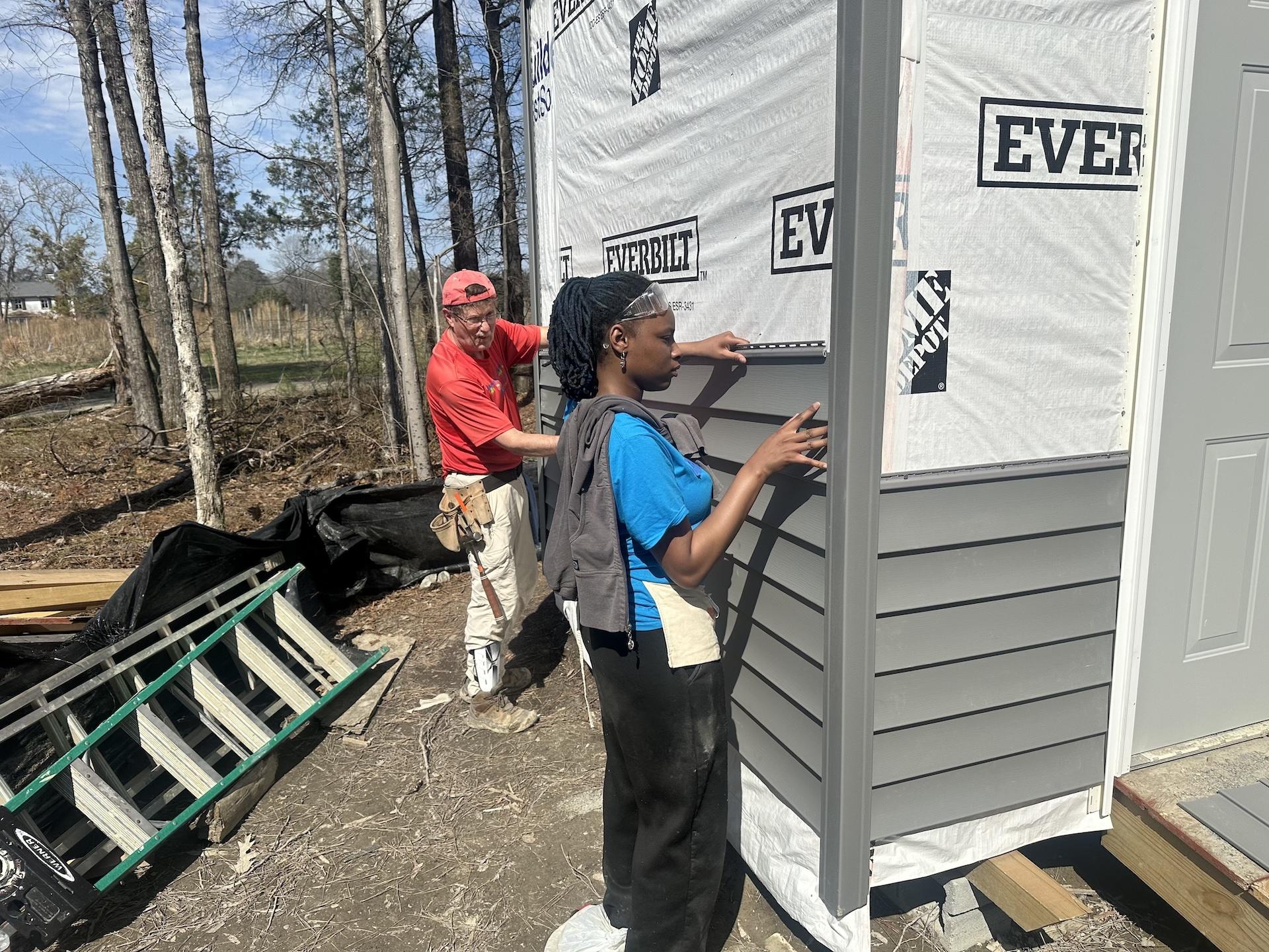 two students putting up siding