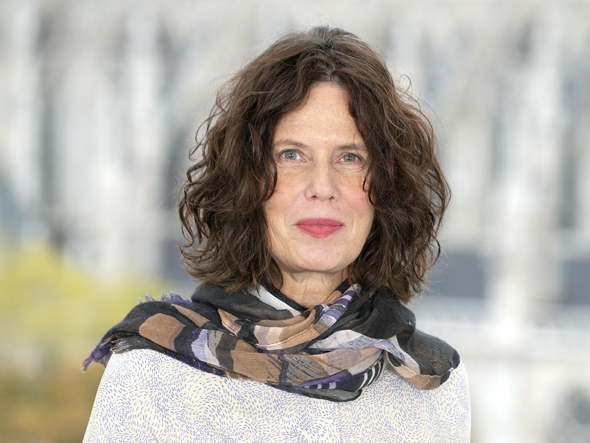 Bettina Brandt wears a white sweater and multi-colored scarf 
