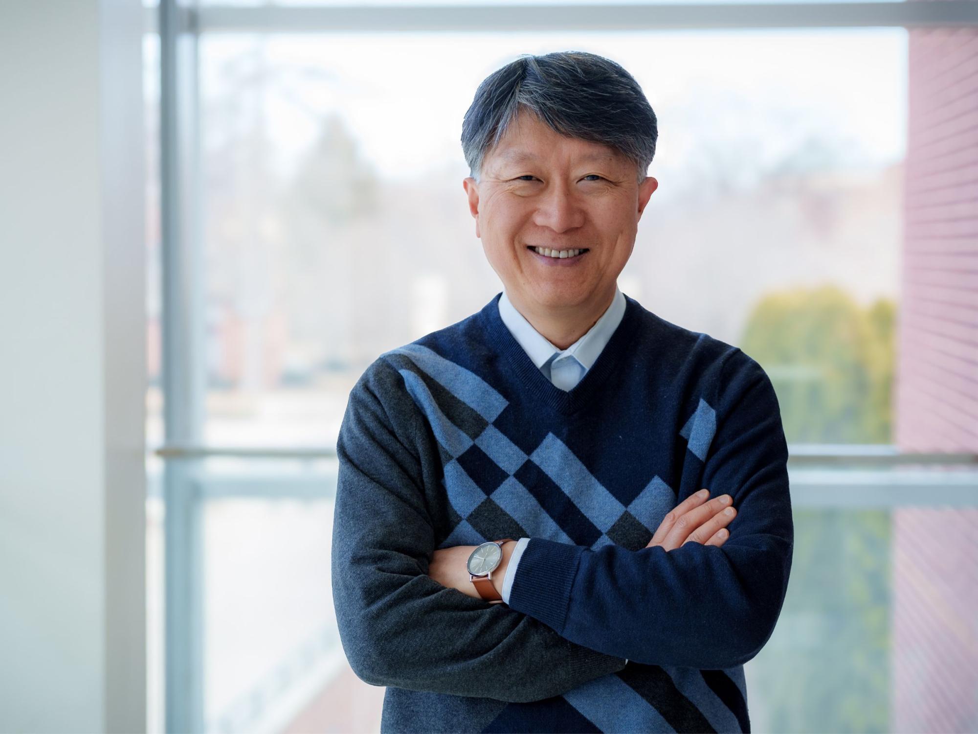person in blue sweater with windows in background