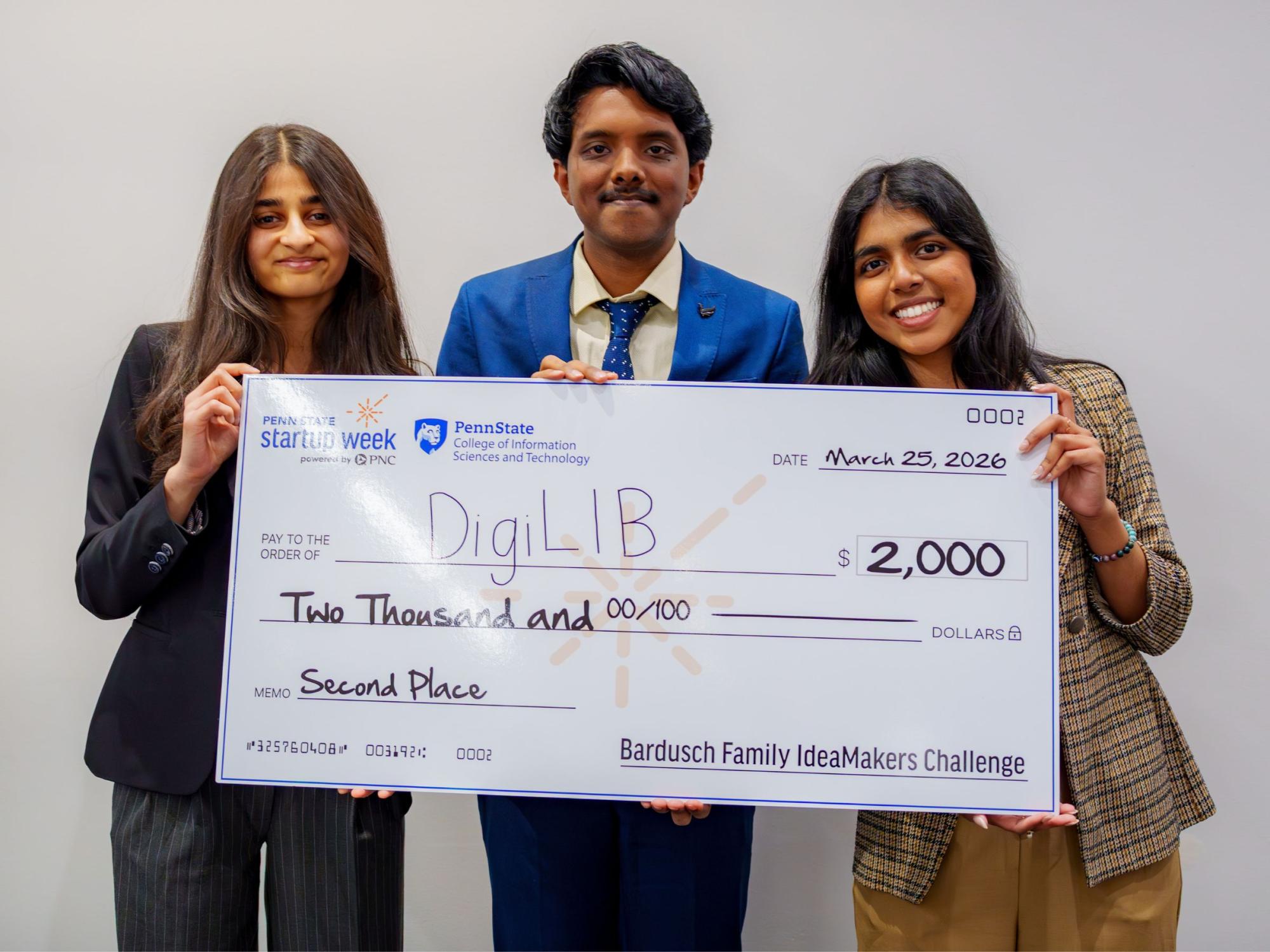 Three people in business attire pose with giant check