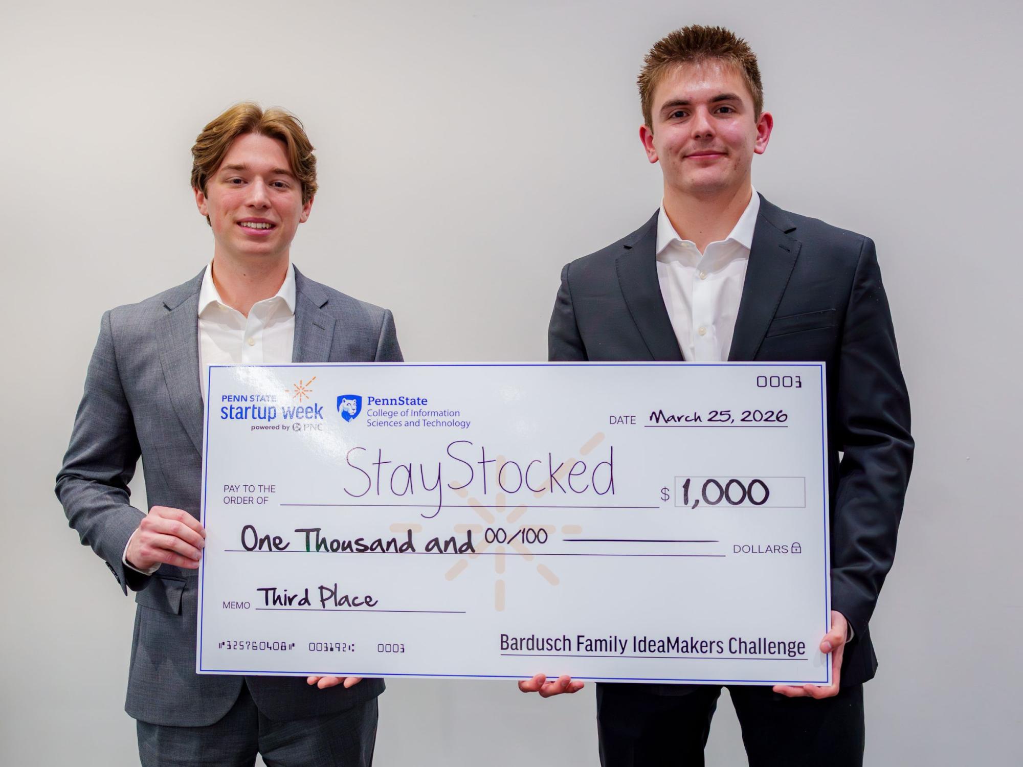 two people in business suits hold giant check
