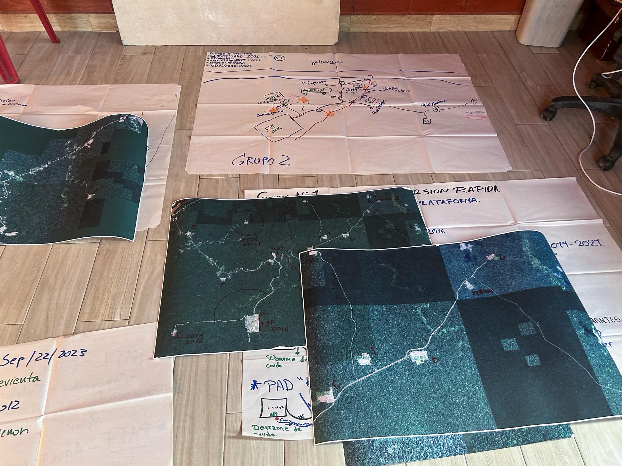 Various maps and diagrams spread out on a tiled floor, displaying hand-drawn annotations and data.