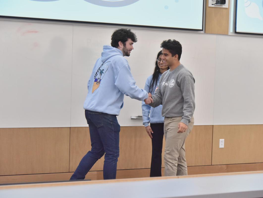 Aryan and hackathon coordinators shake hands after his win