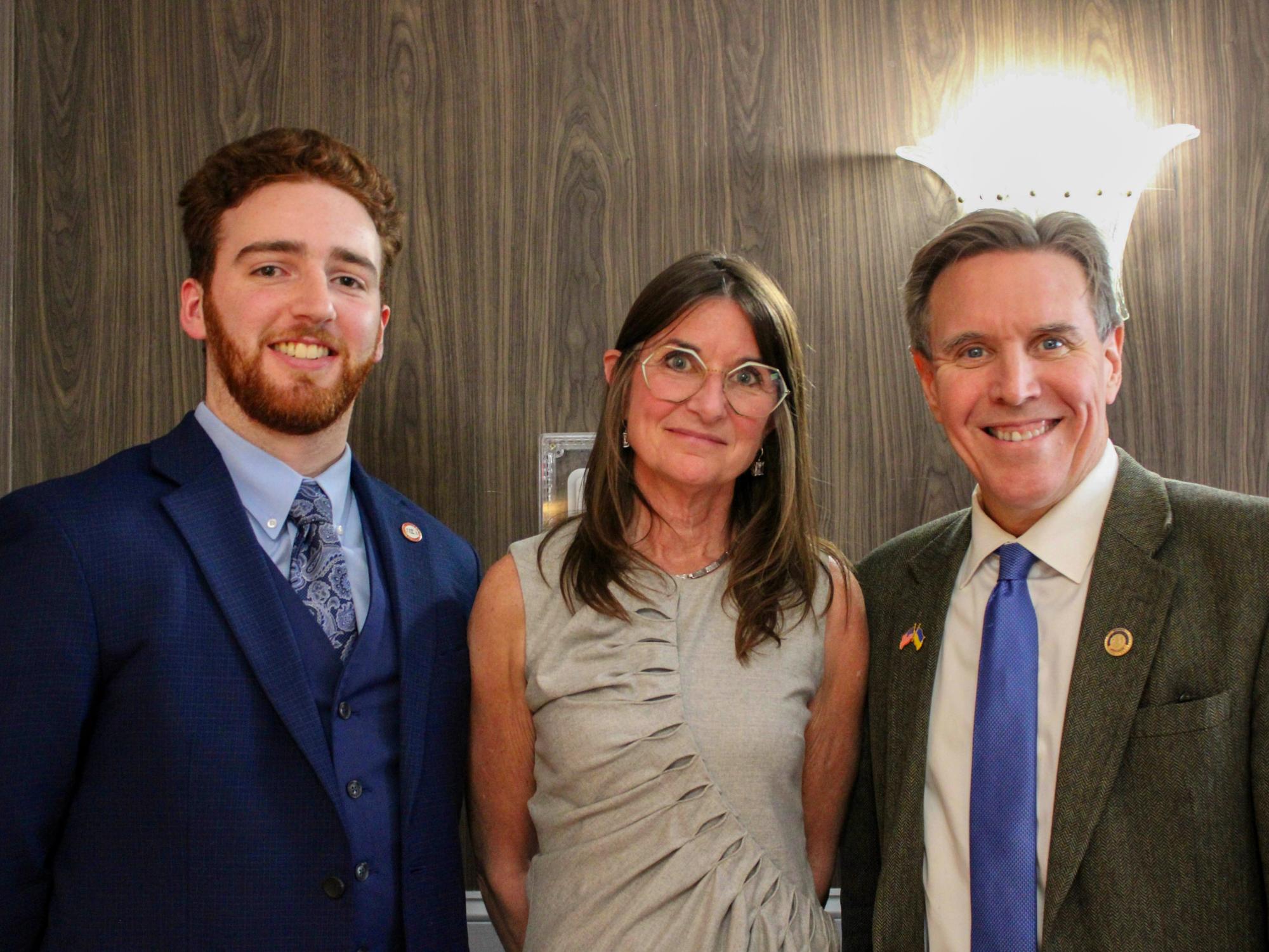 Emmanuel Kraft (left) wears a blue suit and stands with a female faculty member and a male politician dressed in formal attire.