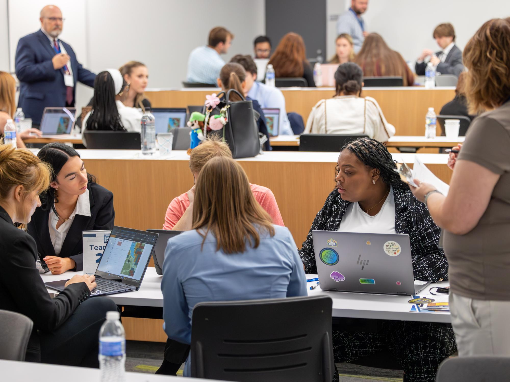 Trinidy Manison, right, sits behind her laptop while interacting with four other students in a lecture hall at the School of Public Policy’s Local Government Expo.