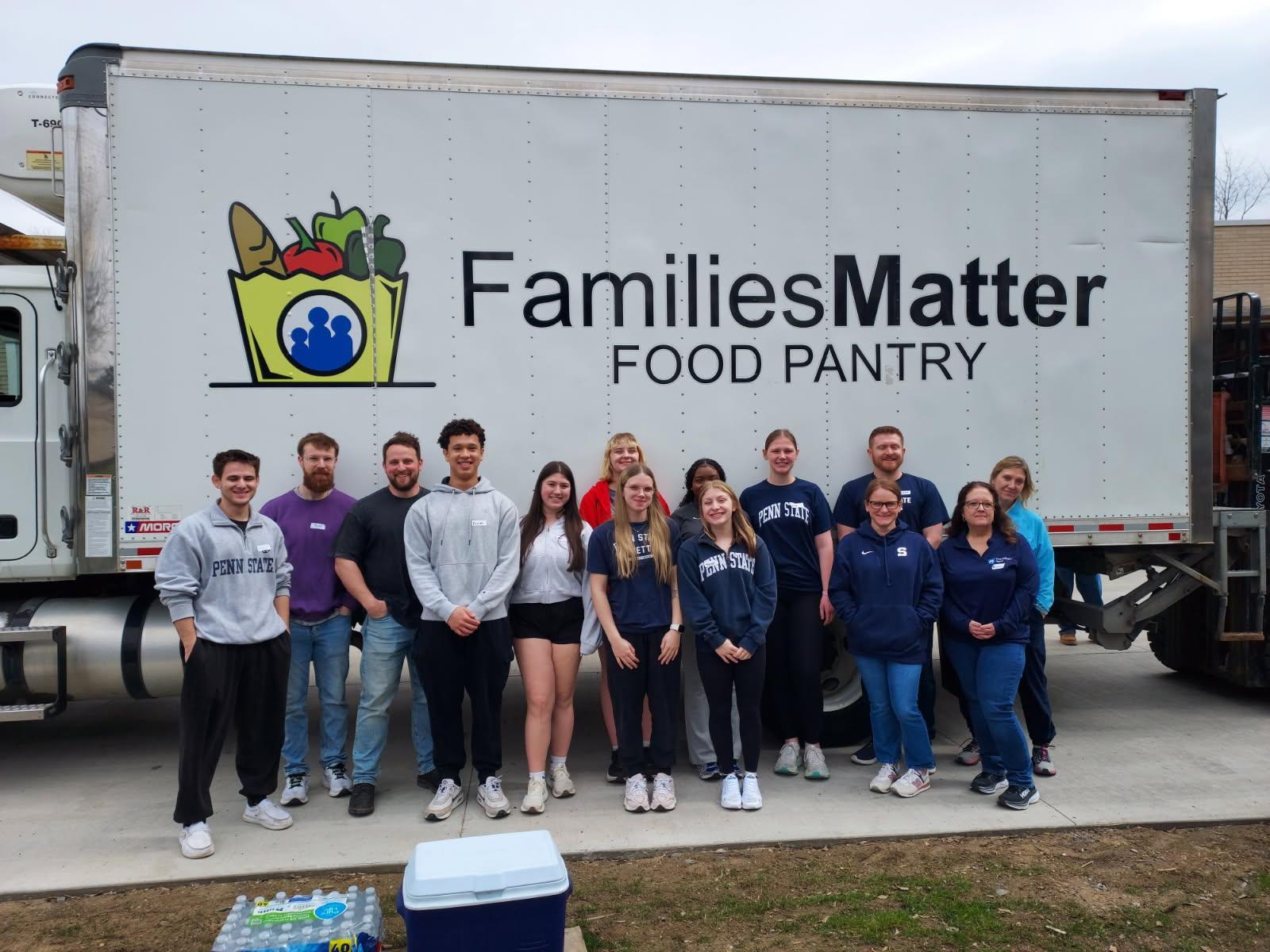Students standing outside in front of a box truck with the words Families Matter Food Pantry printed on the side of it.