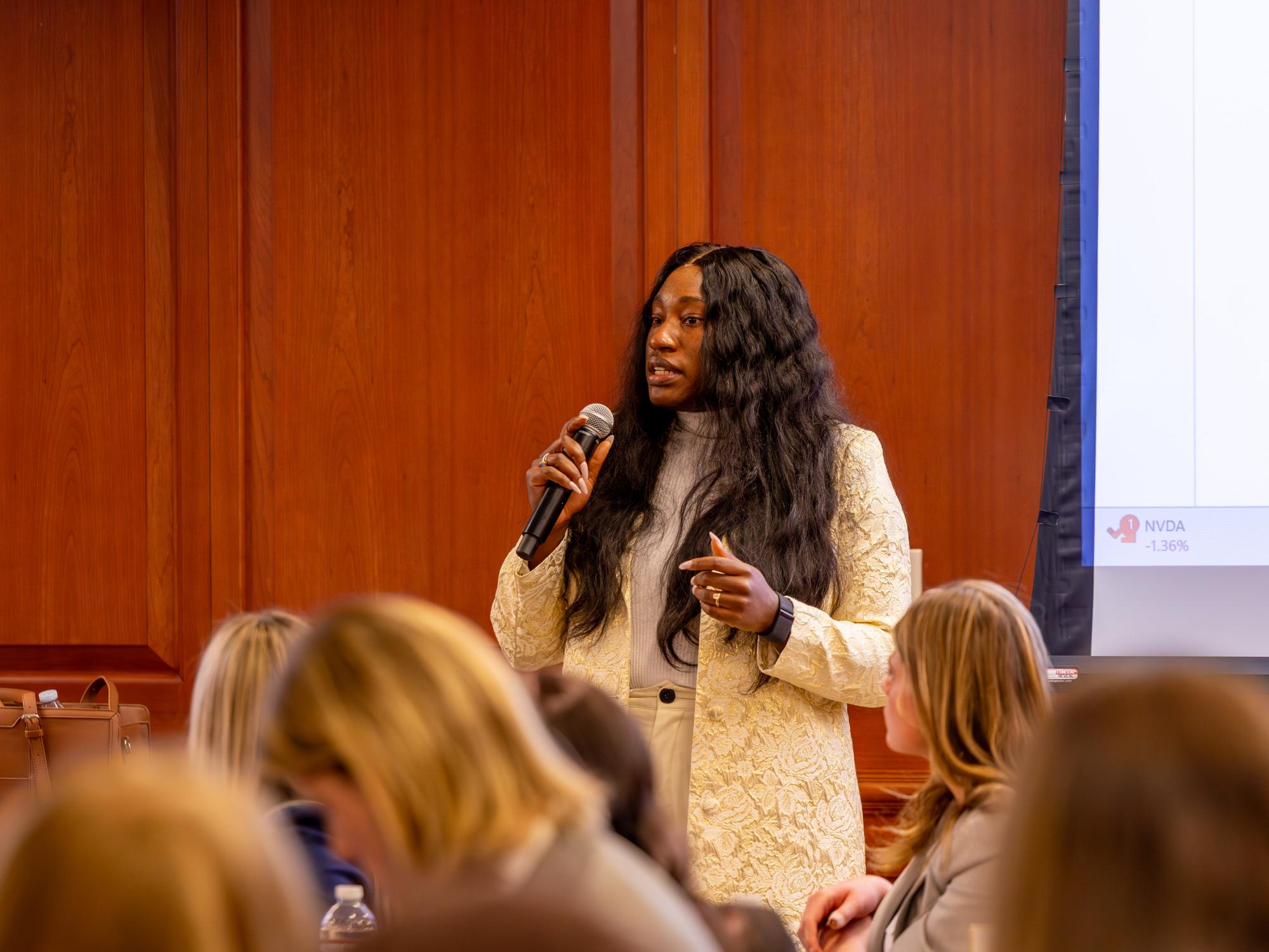 Olivia Umoren Ezeuko speaks into a microphone in front of an audience of students. 