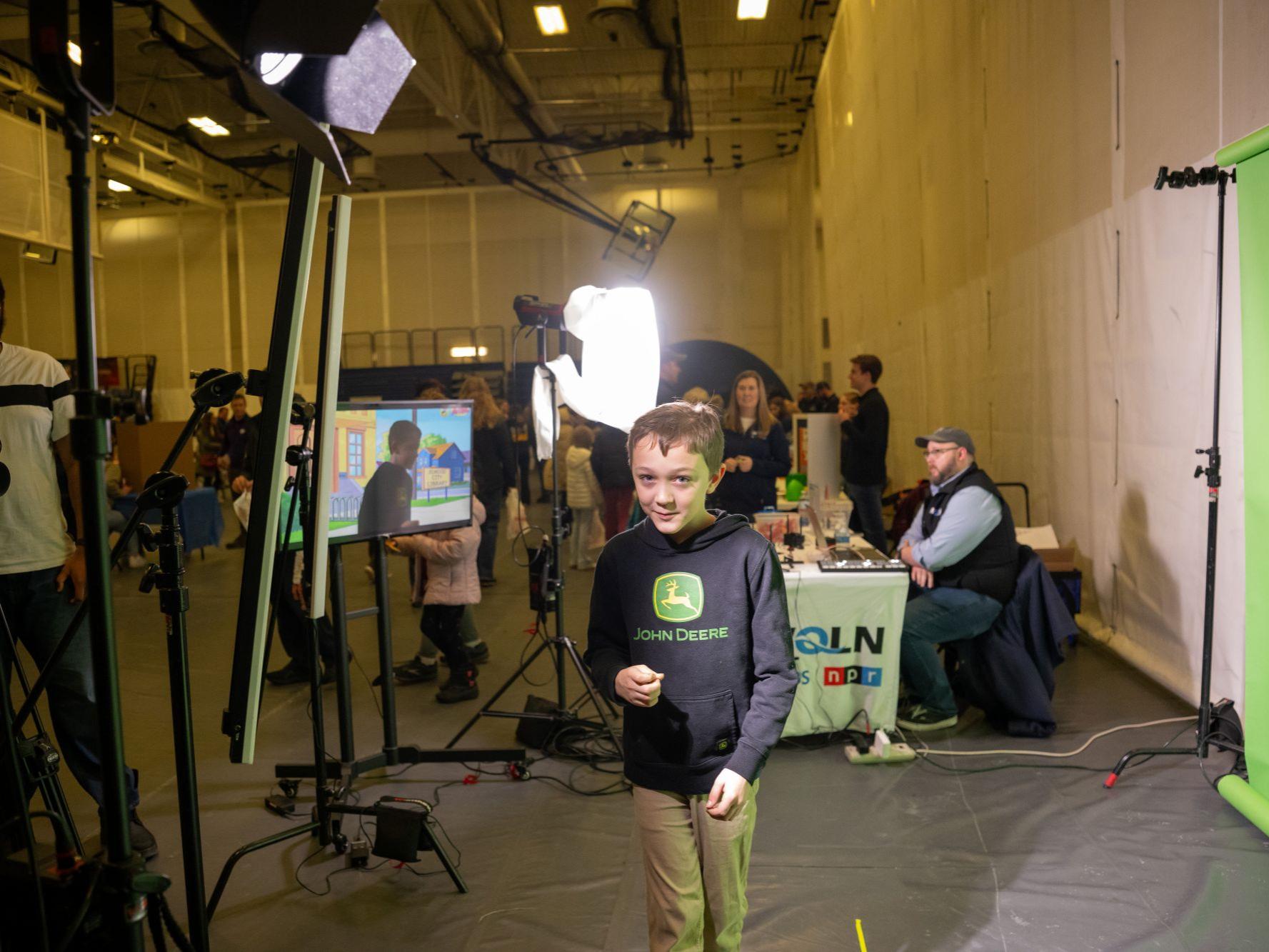 A boy stands in front of a TV green-screen at Penn State Behrend's STEAM Fair