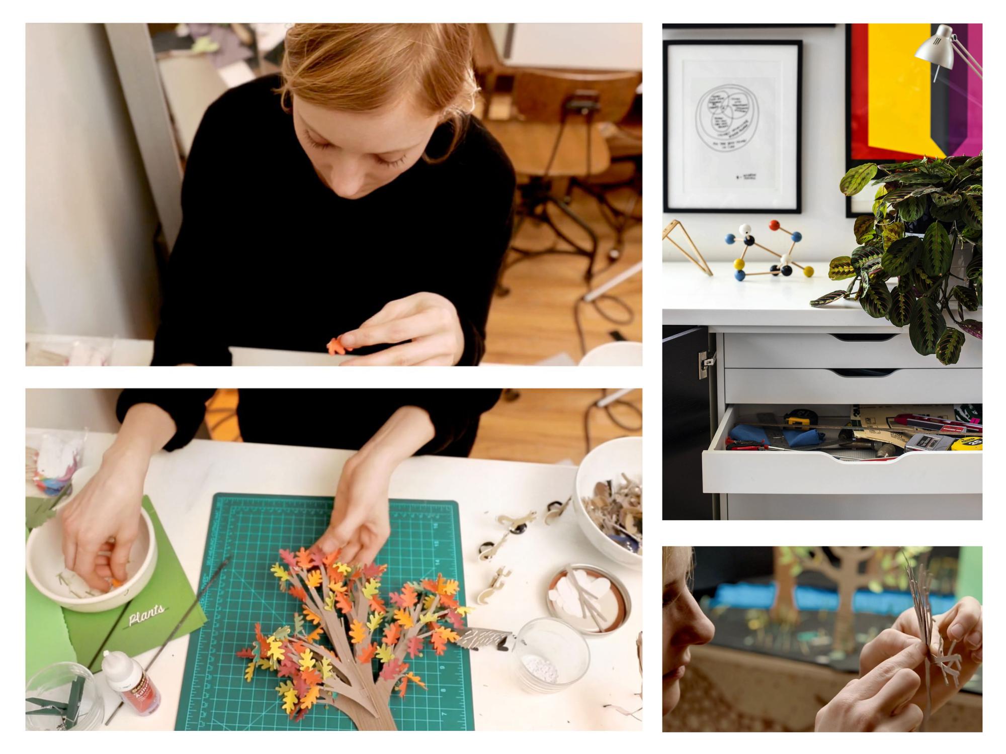 a woman bent over a white desk working with paper art in colorful shapes
