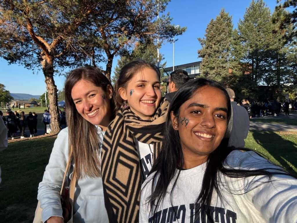 Three female students smile while out tailgating.