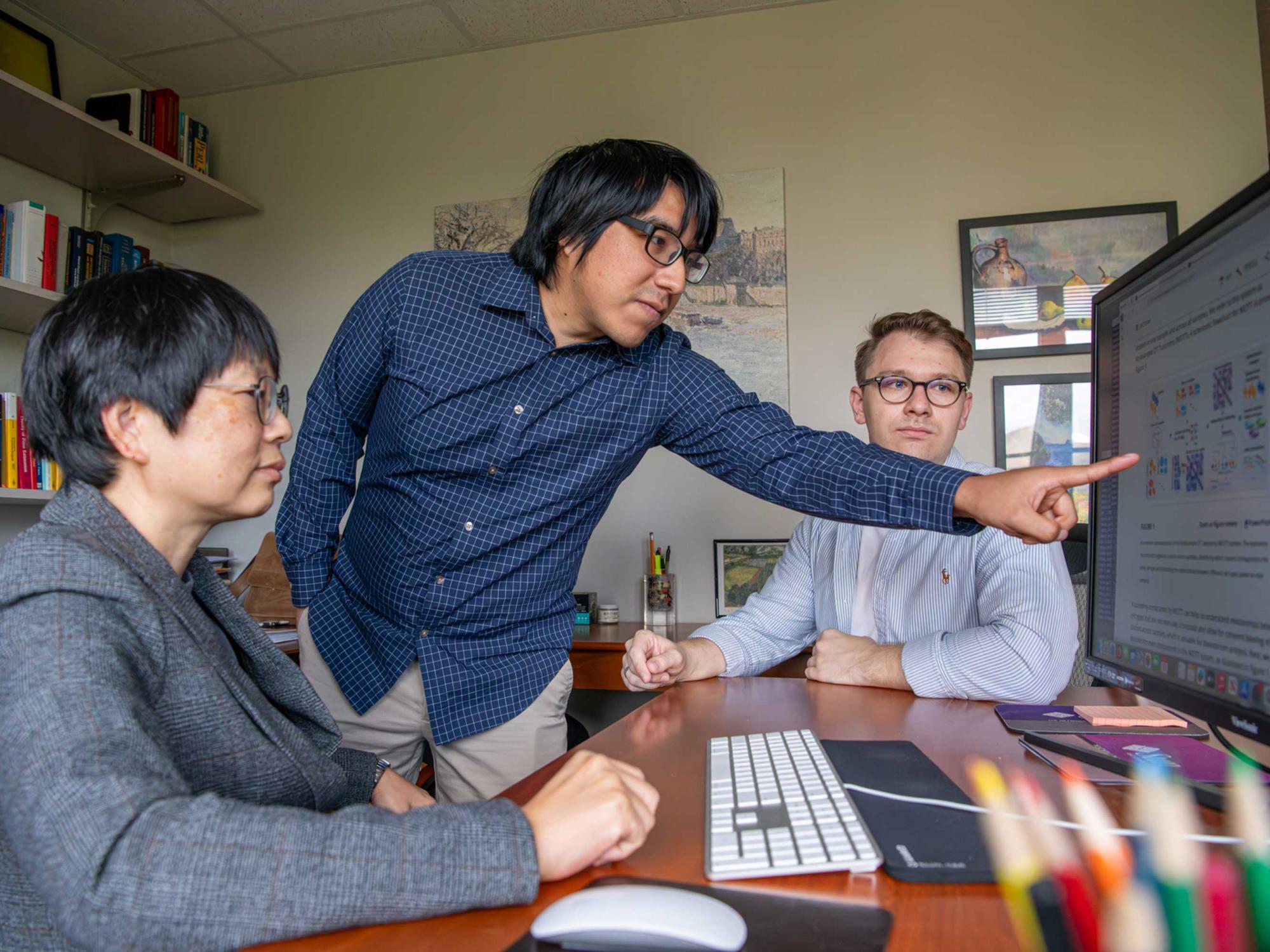 Student points at computer while Jia Li and another student look on