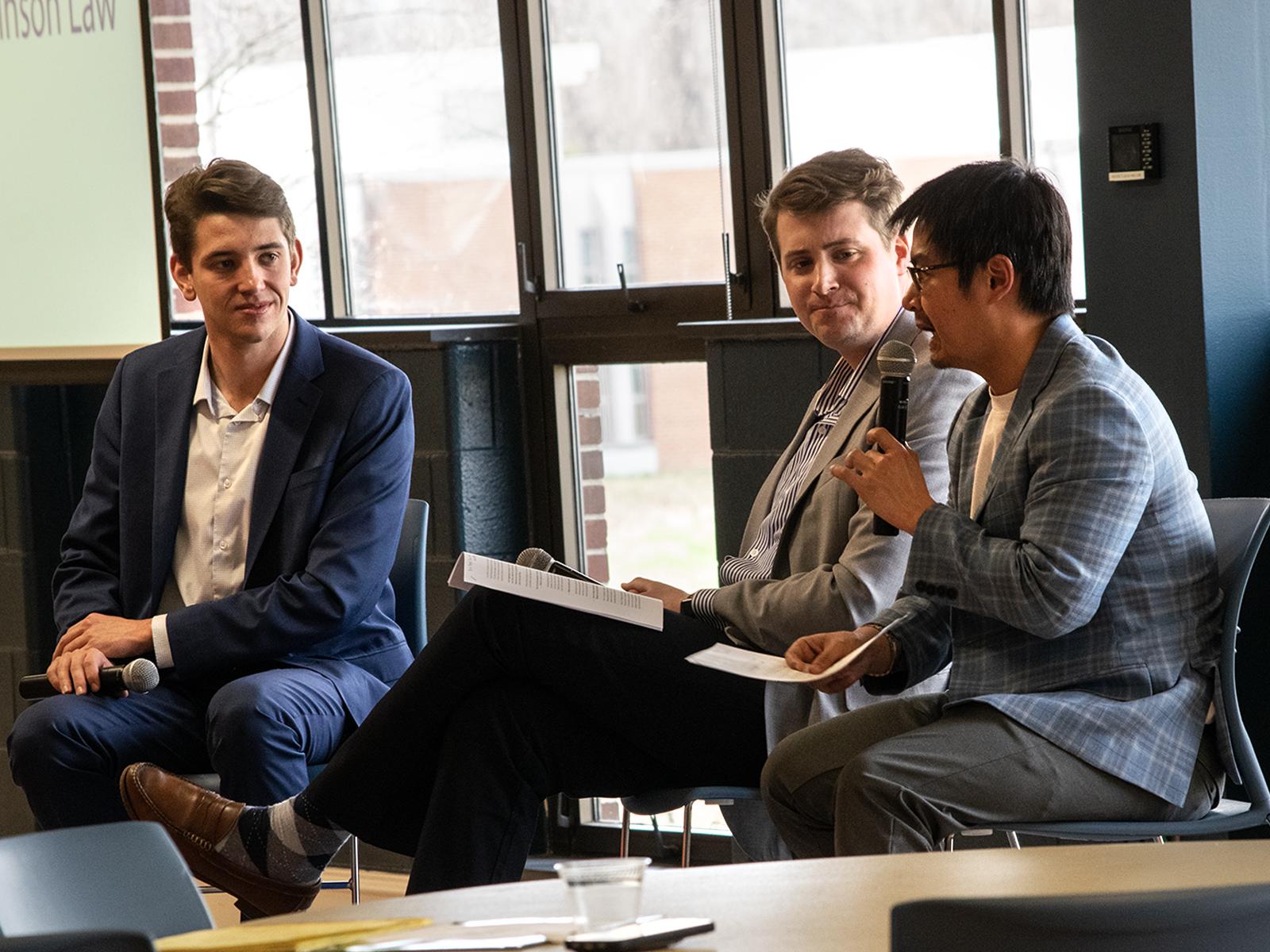 A student and two panelists talk on a stage during a pitch competition
