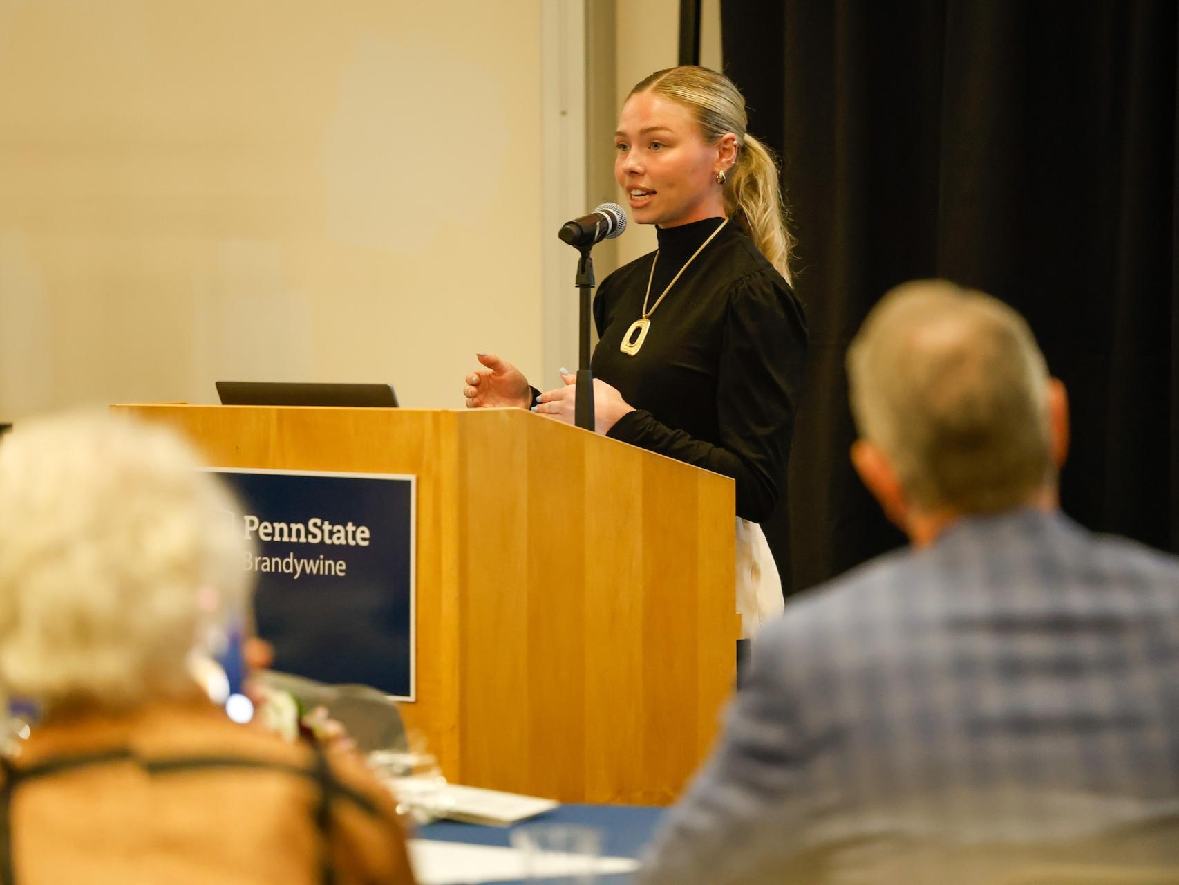 Ava presenting her honors thesis behind a podium