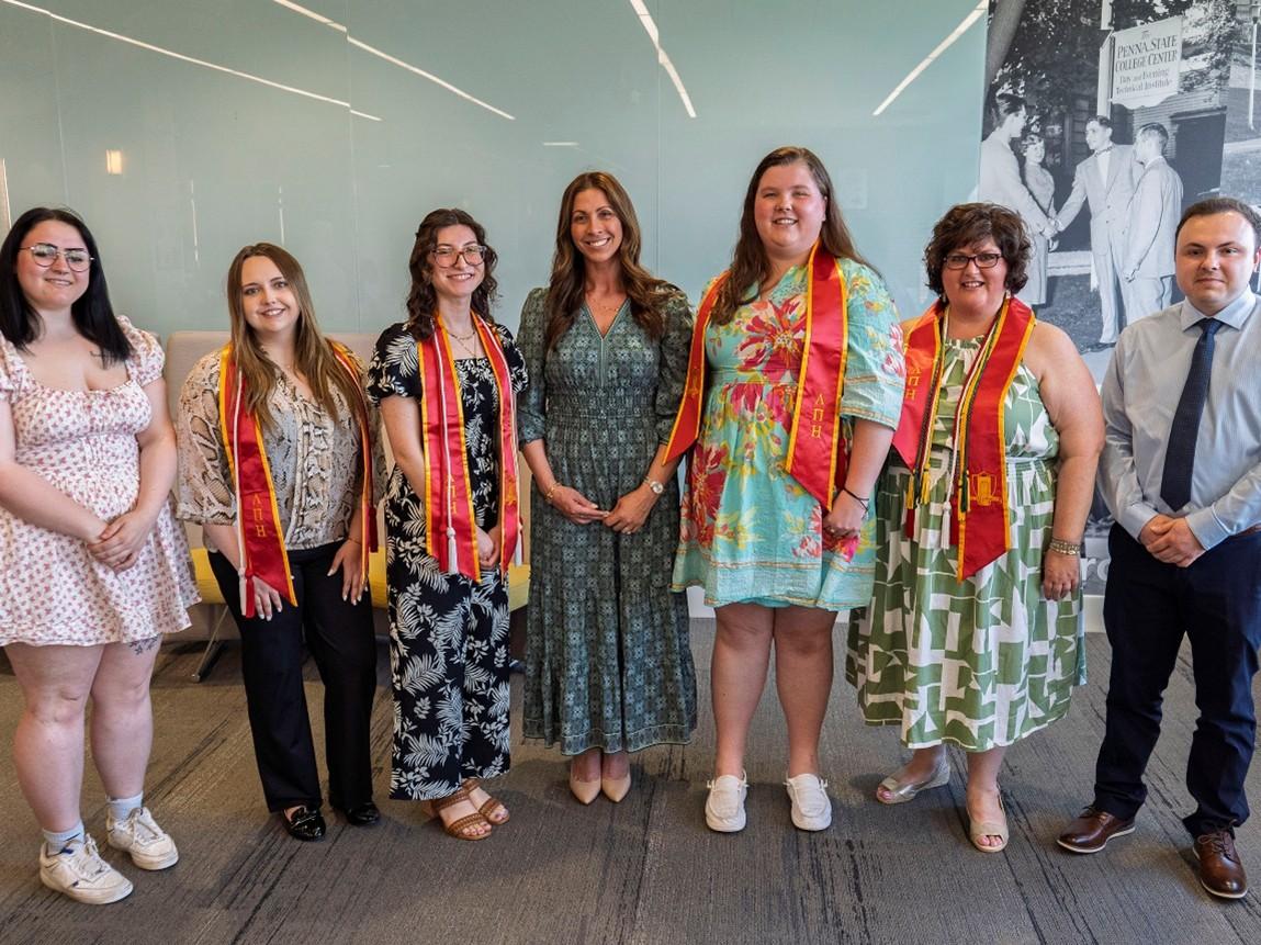 Student inductees and graduating members of Lambda Pi Eta pose for a group photo with Corporate Comm program coordinator Kelly Mazzucca