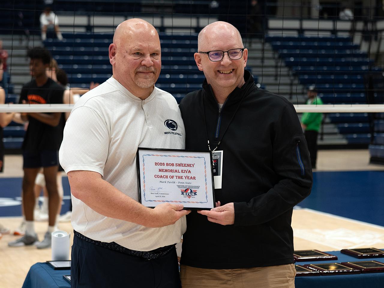 Two men posing with framed award
