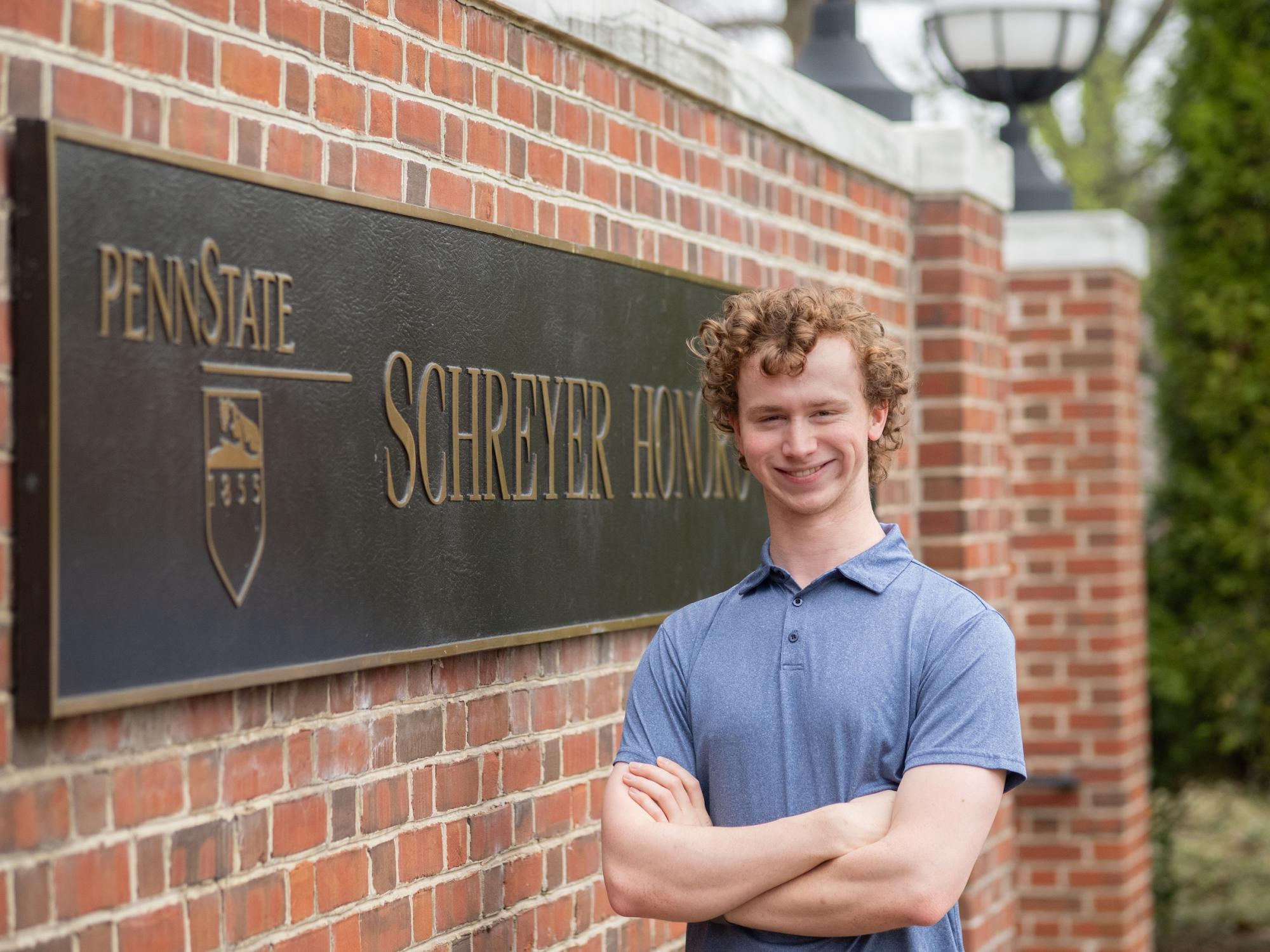 Eric Welp posing in front of Schreyer Honors College sign
