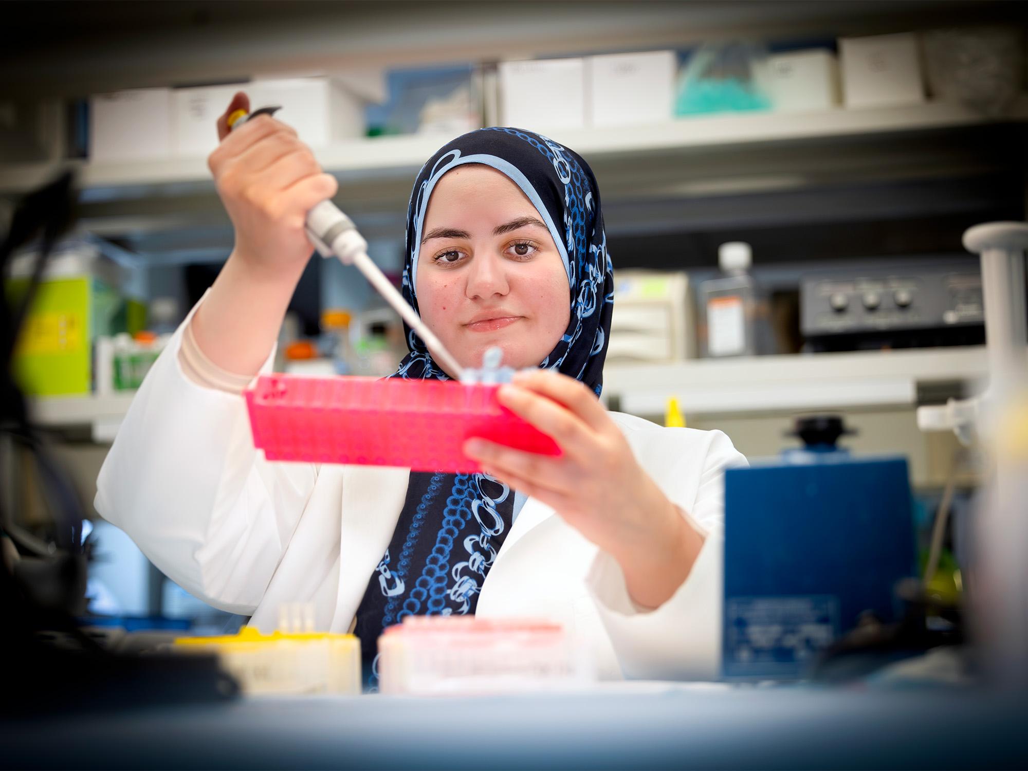 woman using pipette in lab
