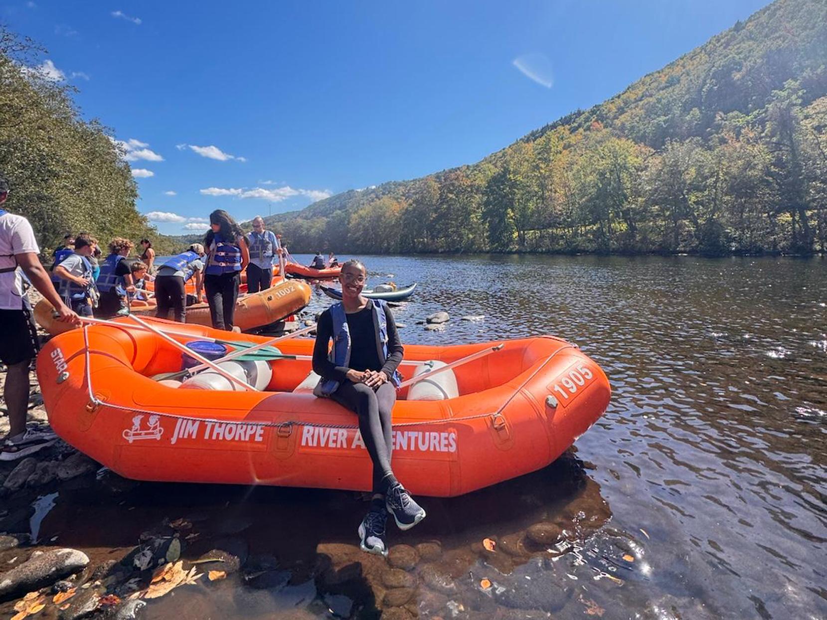 Ajayda Williams sits on a raft on a river