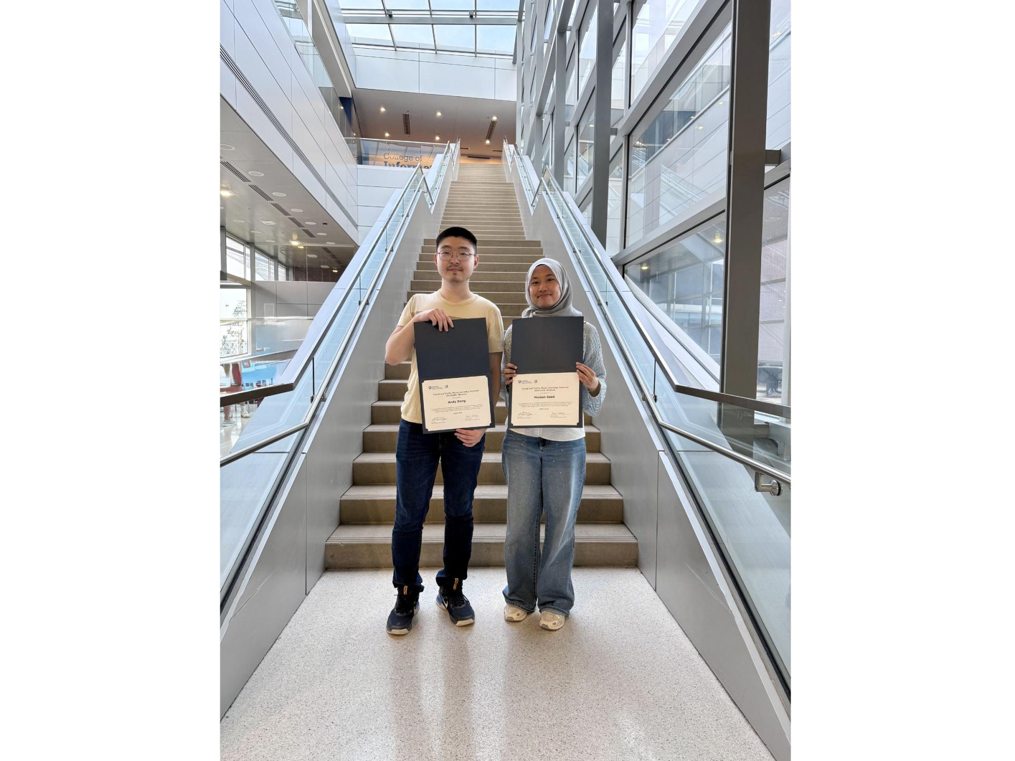 two college students standing on stairs inside campus building