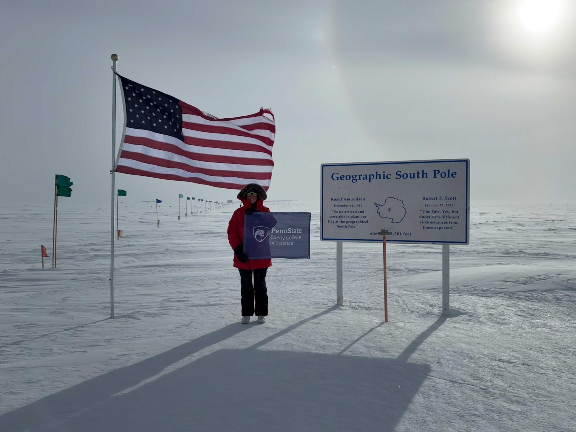 Kayla DeHolton poses at by the sign marking the geographic south pole