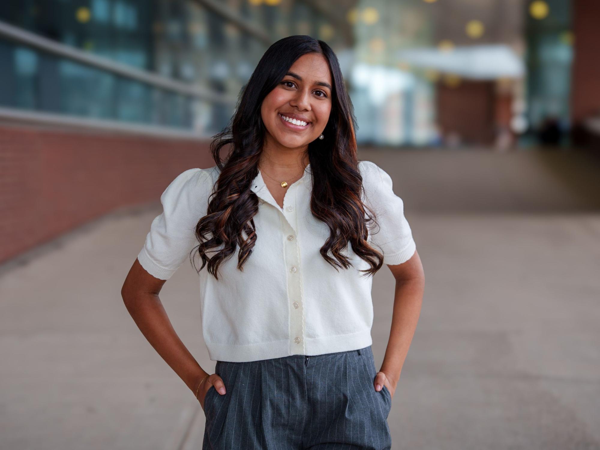 smiling person with long dark hair wearing white shirt and jeans